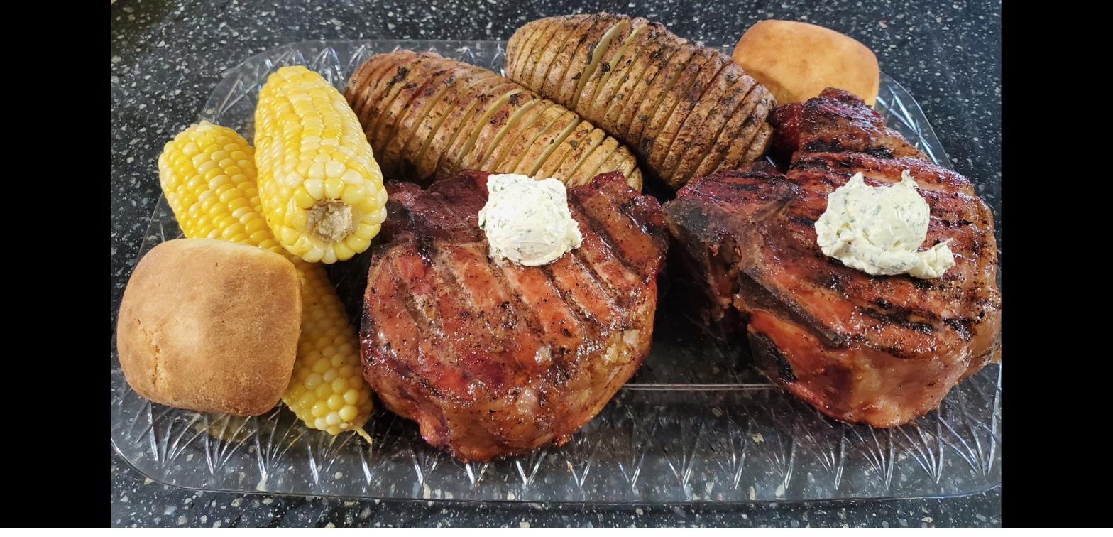 Plated ribeyes with hasselback potatoes and corn